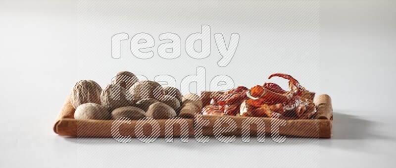 مربعان من أعواد القرفة ممتلئان بالفلفل الحار المجفف وجوزة الطيب علي خلفية بيضاء