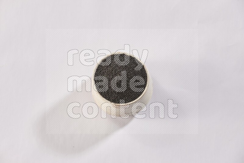 A beige pottery bowl full of black seeds on white flooring