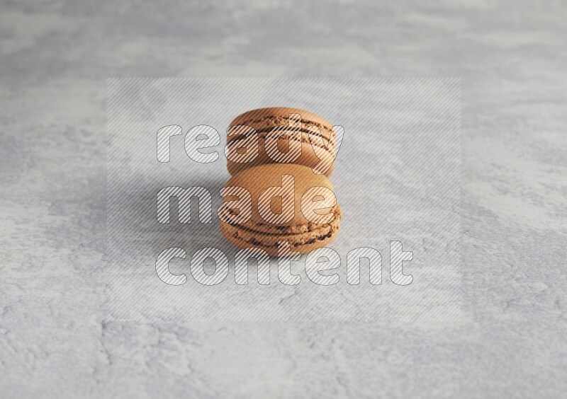 45º Shot of two Brown Coffee macarons  on white  marble background