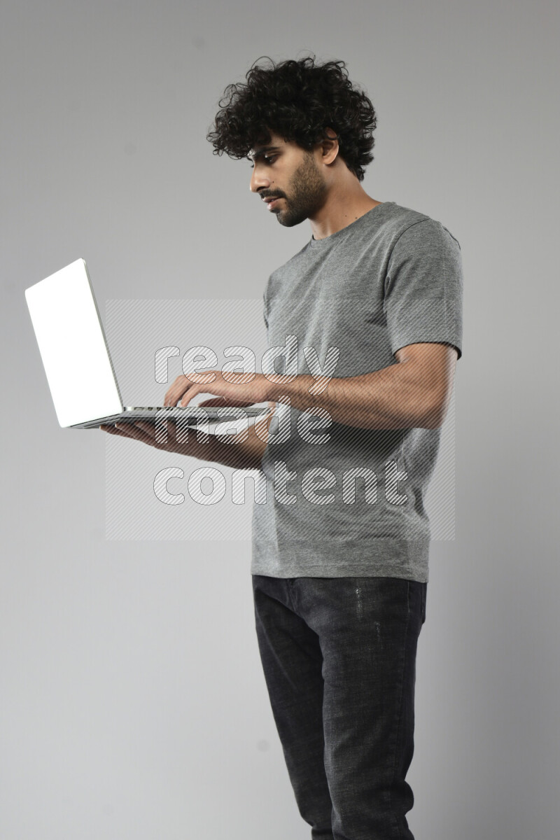A man wearing casual standing and working on a laptop on white background