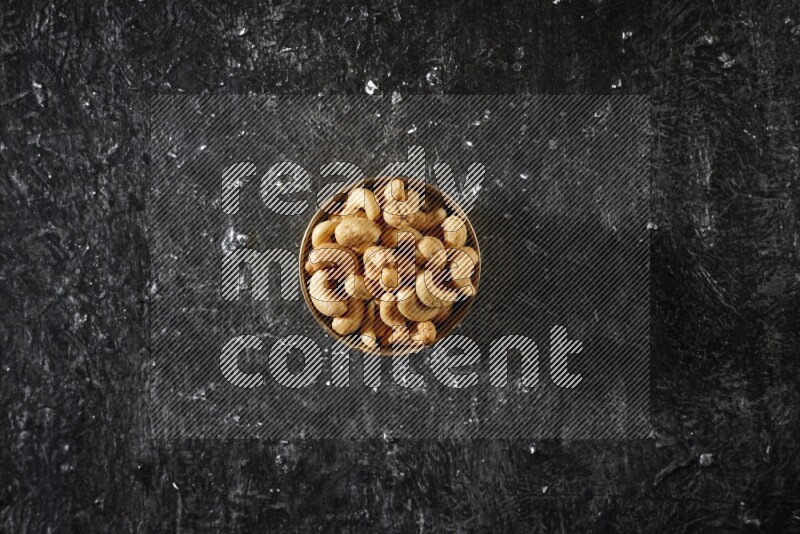 Nuts in a metal bowl in a dark setup