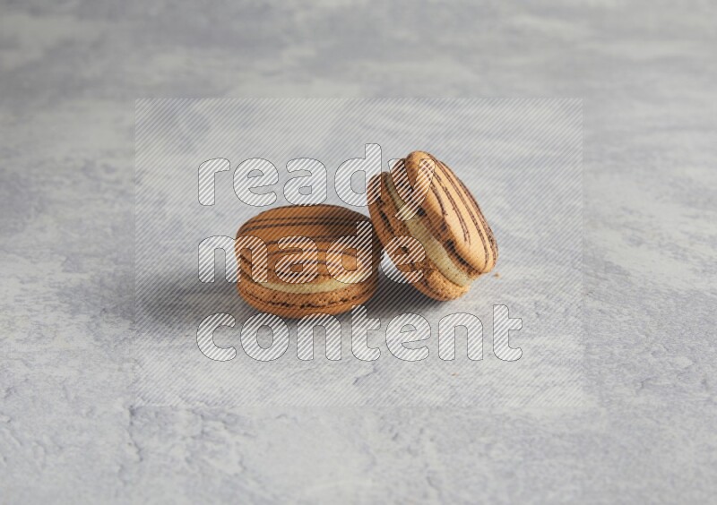 45º Shot of two light brown  Almond Cream macarons  on white  marble background