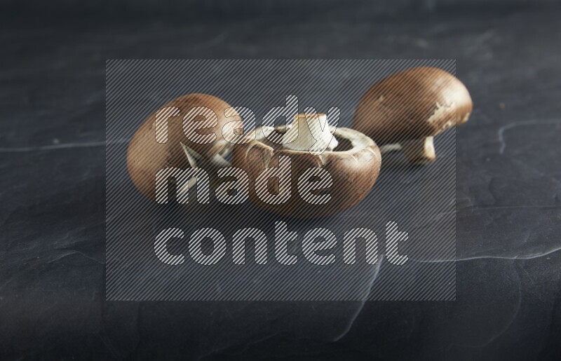 45 degre cremini  mushrooms on a textured black slate background
