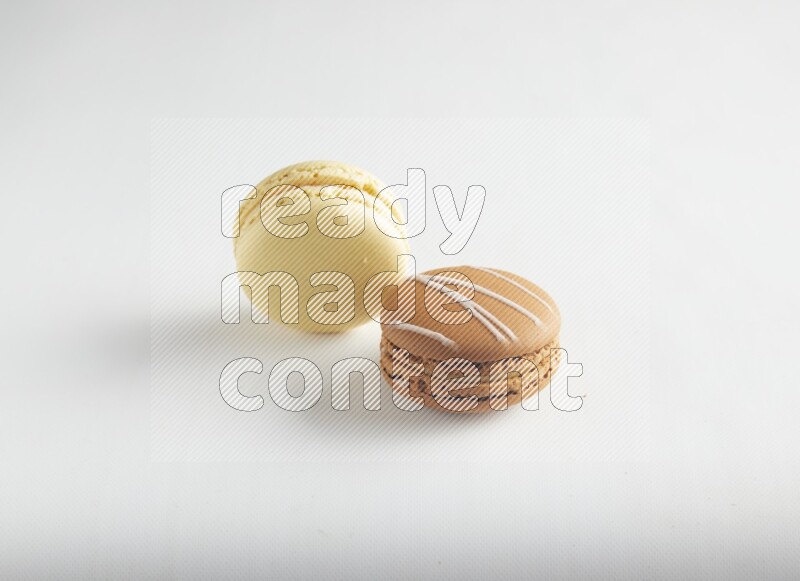 45º Shot of of two assorted Brown Irish Cream, and Yellow Vanilla macarons on white background