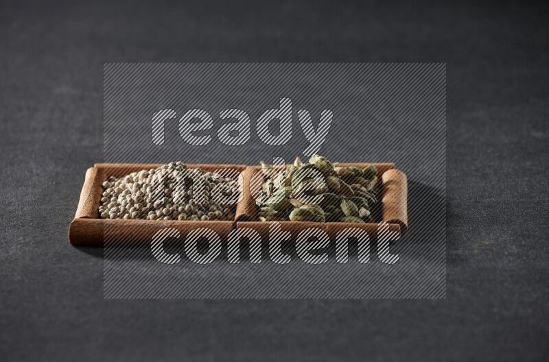 2 squares of cinnamon sticks full of white peppers and cardamom on black flooring