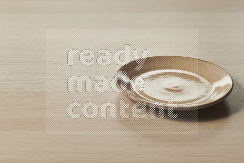 A beige pottery plate on light wooden background