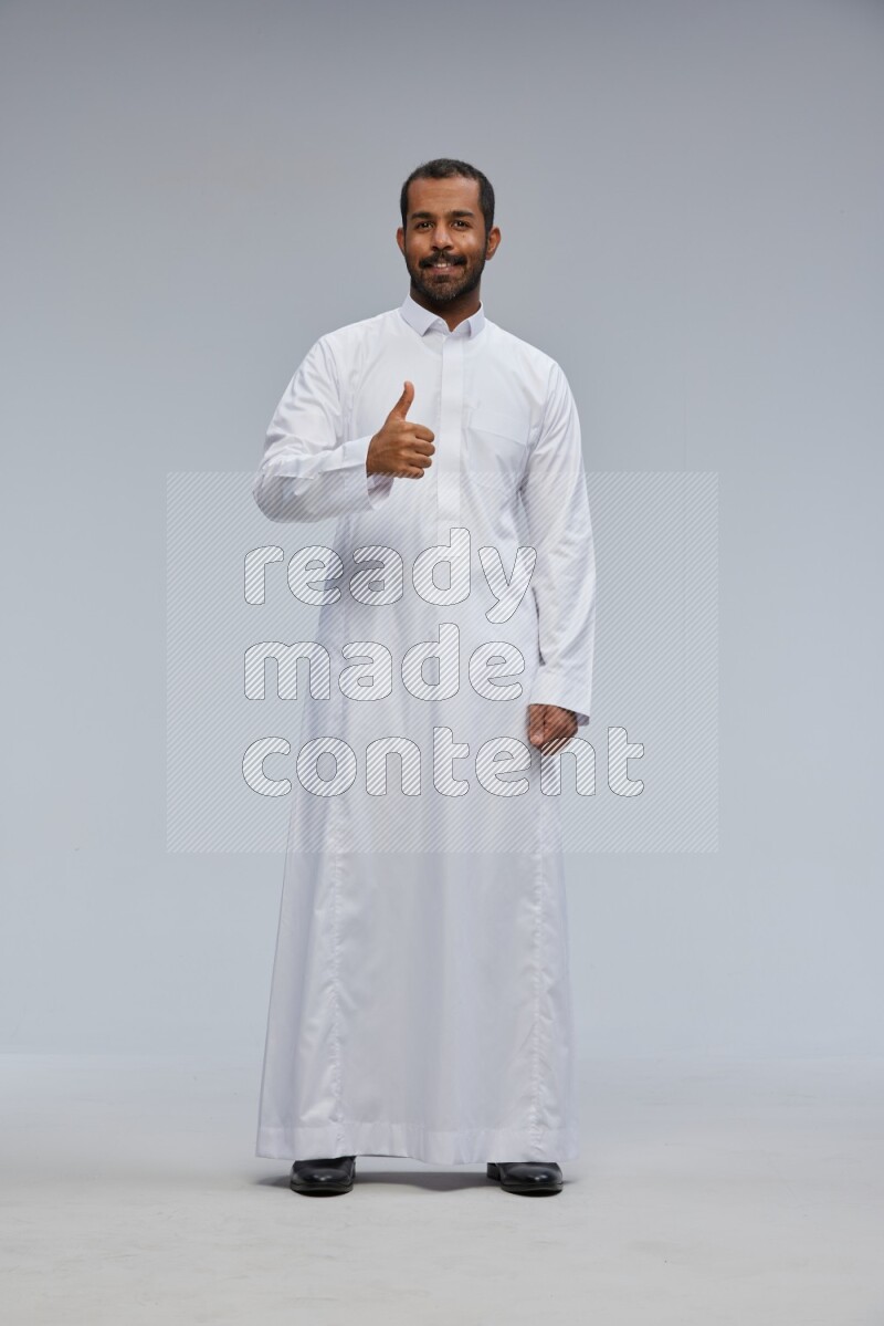 Saudi man Wearing Thob standing interacting with the camera on Gray background
