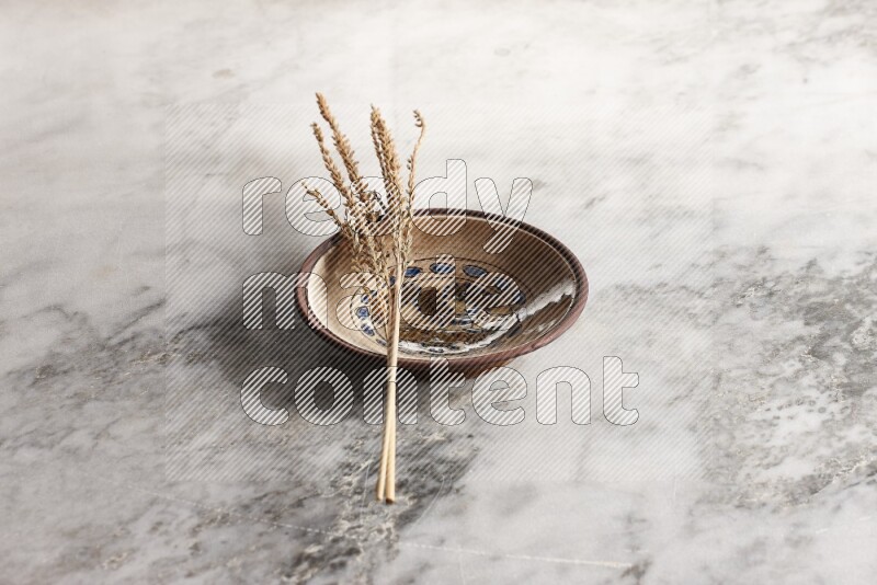 Wheat stalks on decorative pottery plate on grey marble background