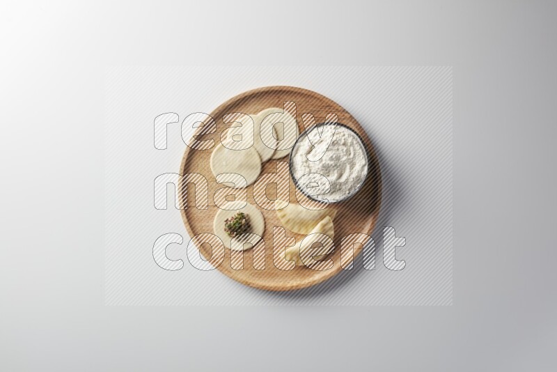 two closed sambosas and one open sambosa filled with meat while flour aside in a wooden dish on a white background