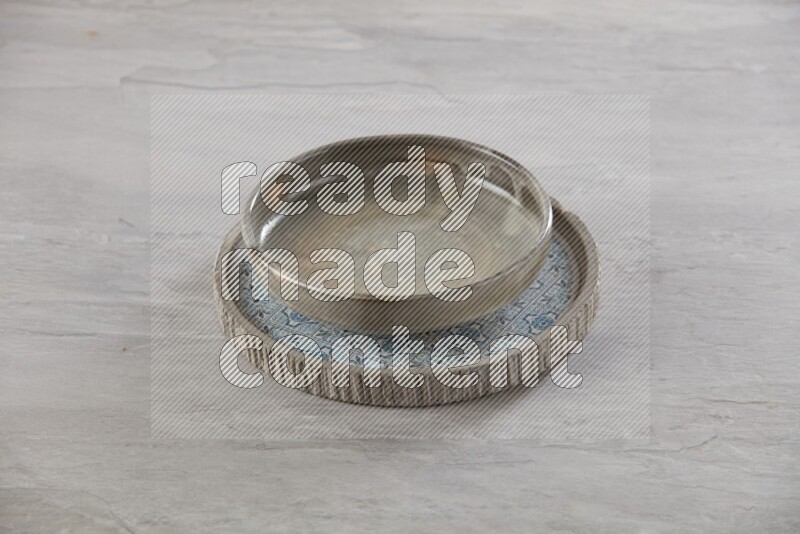 multi color pottery round dish on top of multi color round ceramic plate, on grey textured countertop