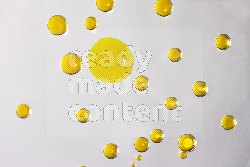 Close-ups of abstract yellow watercolor drops on oil Surface on white background