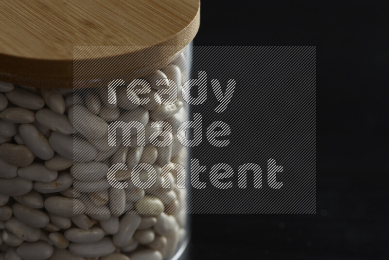 White beans in a glass jar on black background