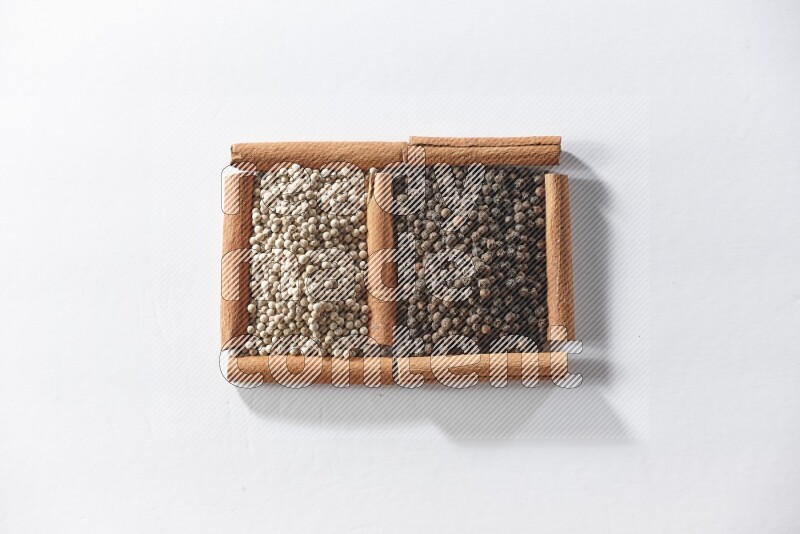 2 squares of cinnamon sticks full of black pepper and white pepper on white flooring