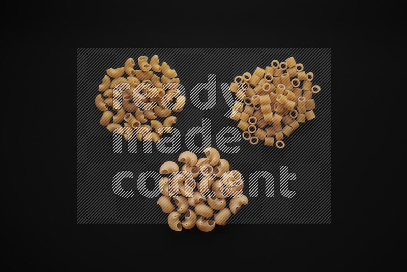 Different pasta types in bunches on black background