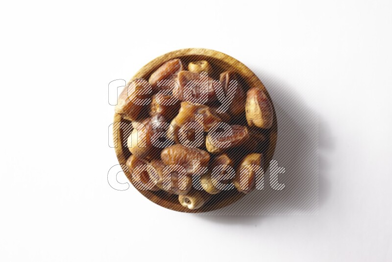 Dates in a wooden bowl on white background