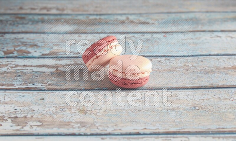 45º Shot of two Pink Litchi Raspberry macarons on light blue wooden background