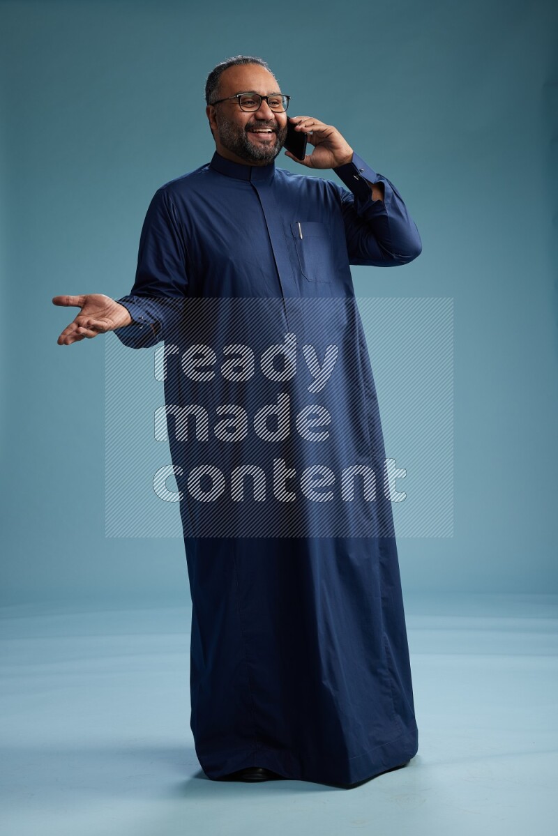 Saudi Man without shimag Standing talking on phone on blue background