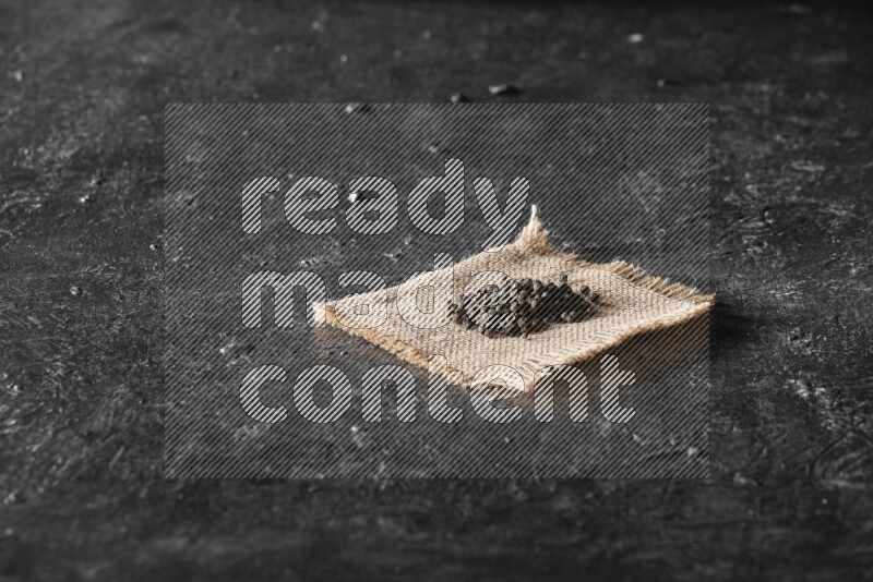 حبوب الفلفل الأسود علي قطعة من الخيش علي خلفية سوداء