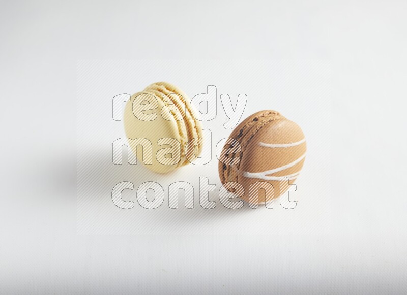 45º Shot of of two assorted Brown Irish Cream, and Yellow Vanilla macarons on white background