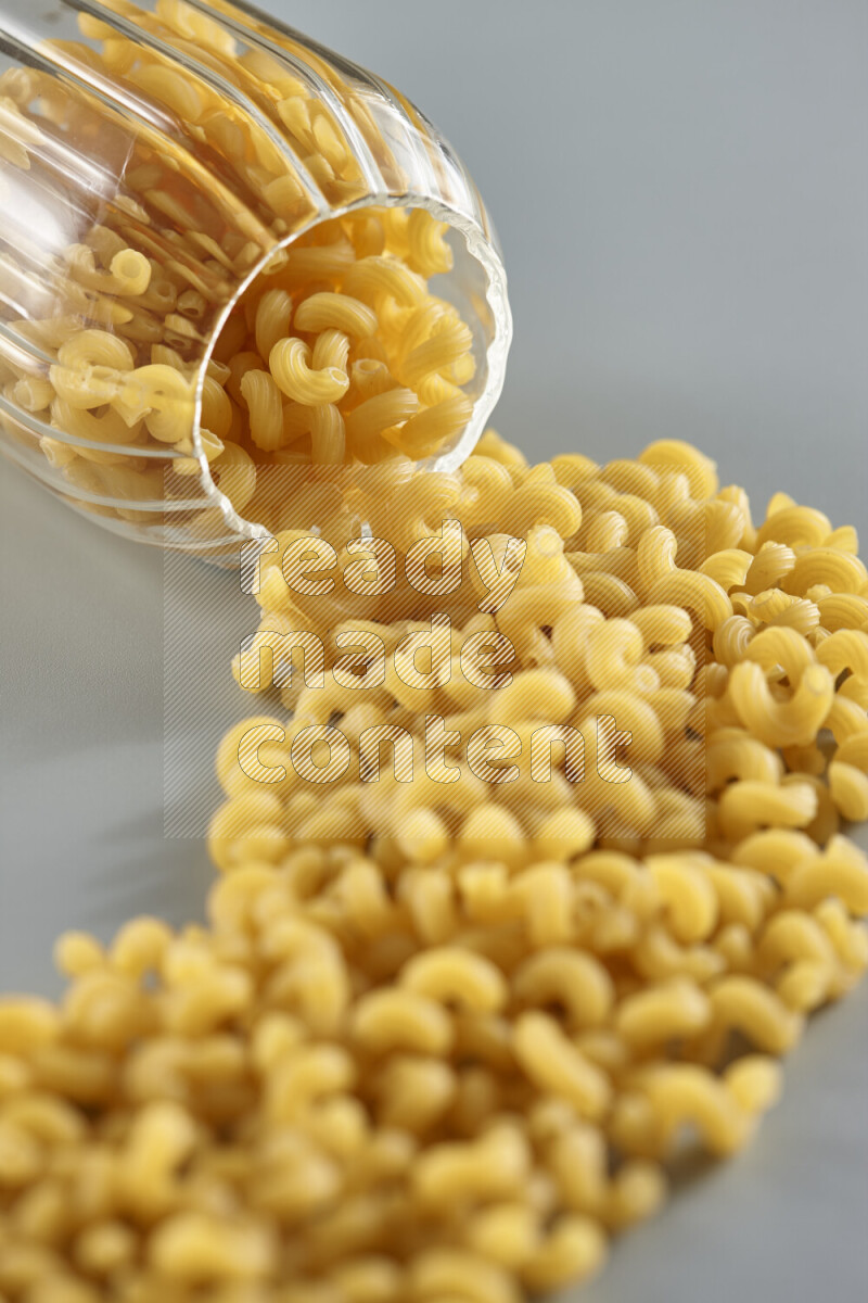 Flipped jar full of raw pasta on light blue background