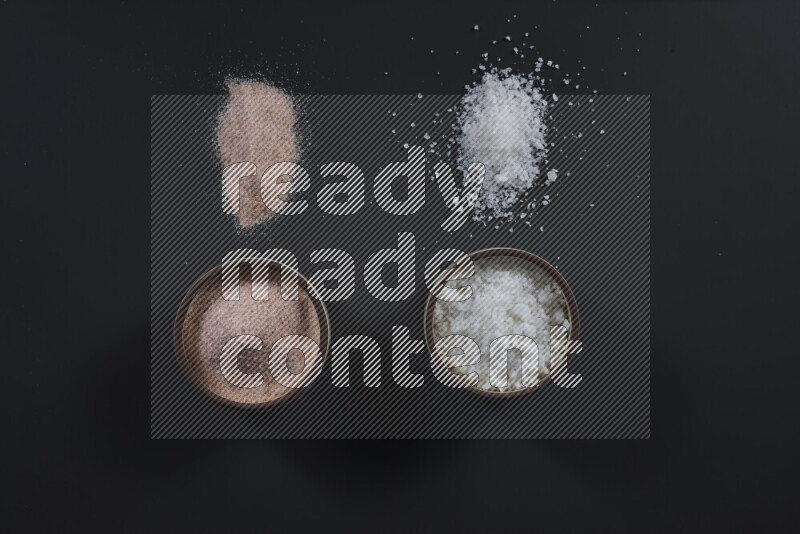 2 pottery bowls one is filled with himalayan salt and the other with white salt on black background