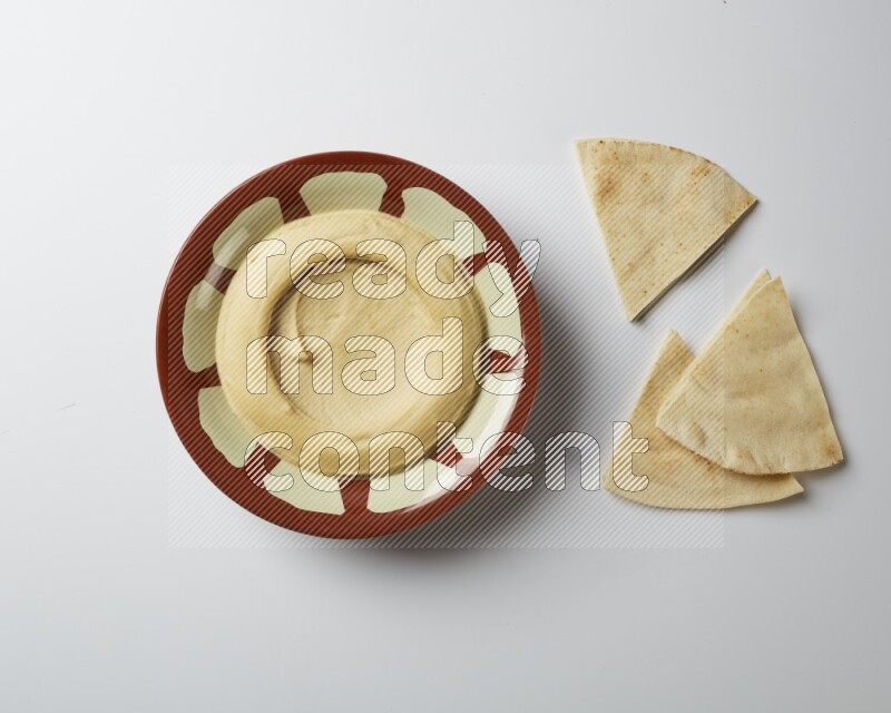 Plain hummus in a traditional plate on a white background