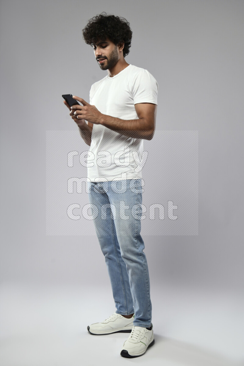 A man wearing casual standing and texting on the phone on white background