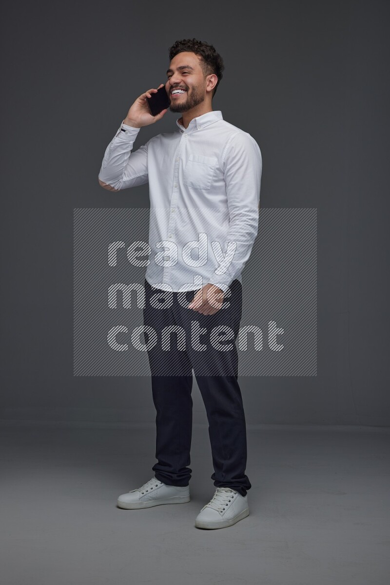 A man wearing smart casual talking in the phone eye level on a gray background