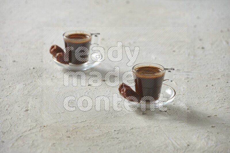 A coffee glass cup with dates and tea on textured white background