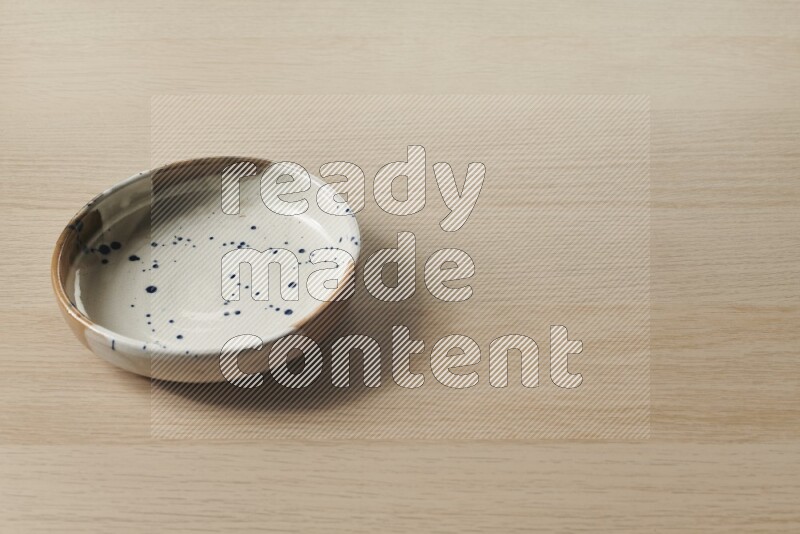 A multicolored pottery bowl on light wooden background