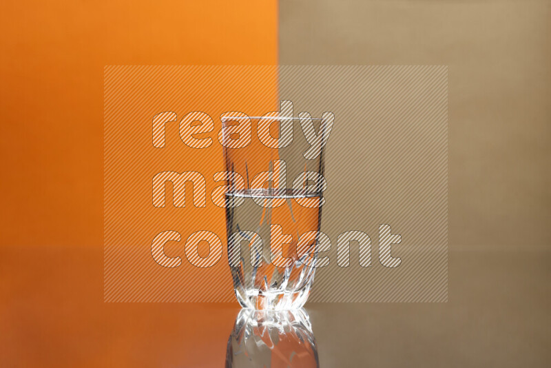 The image features a clear glassware filled with water, set against orange and beige background