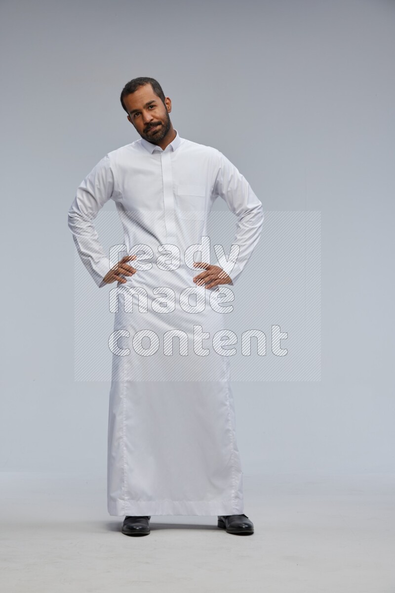 Saudi man Wearing Thob standing interacting with the camera on Gray background