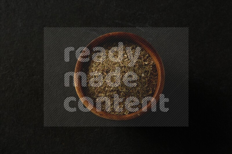 wooden round sauce bowl filled with herbs on grey textured countertop