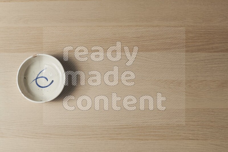 A multicolored pottery bowl on light wooden background