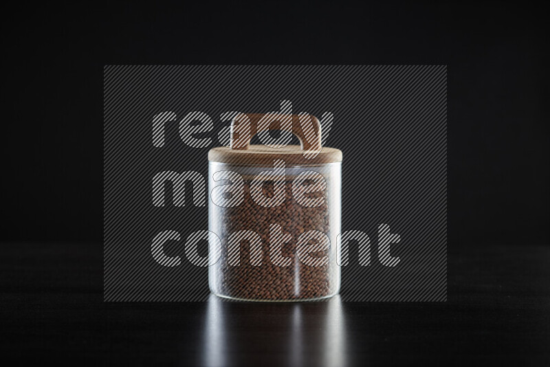 Brown lentils in a glass jar on black background