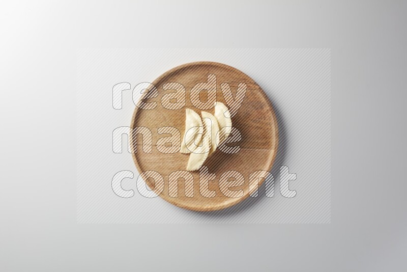 Four Sambosas on a wooden round plate on a white background