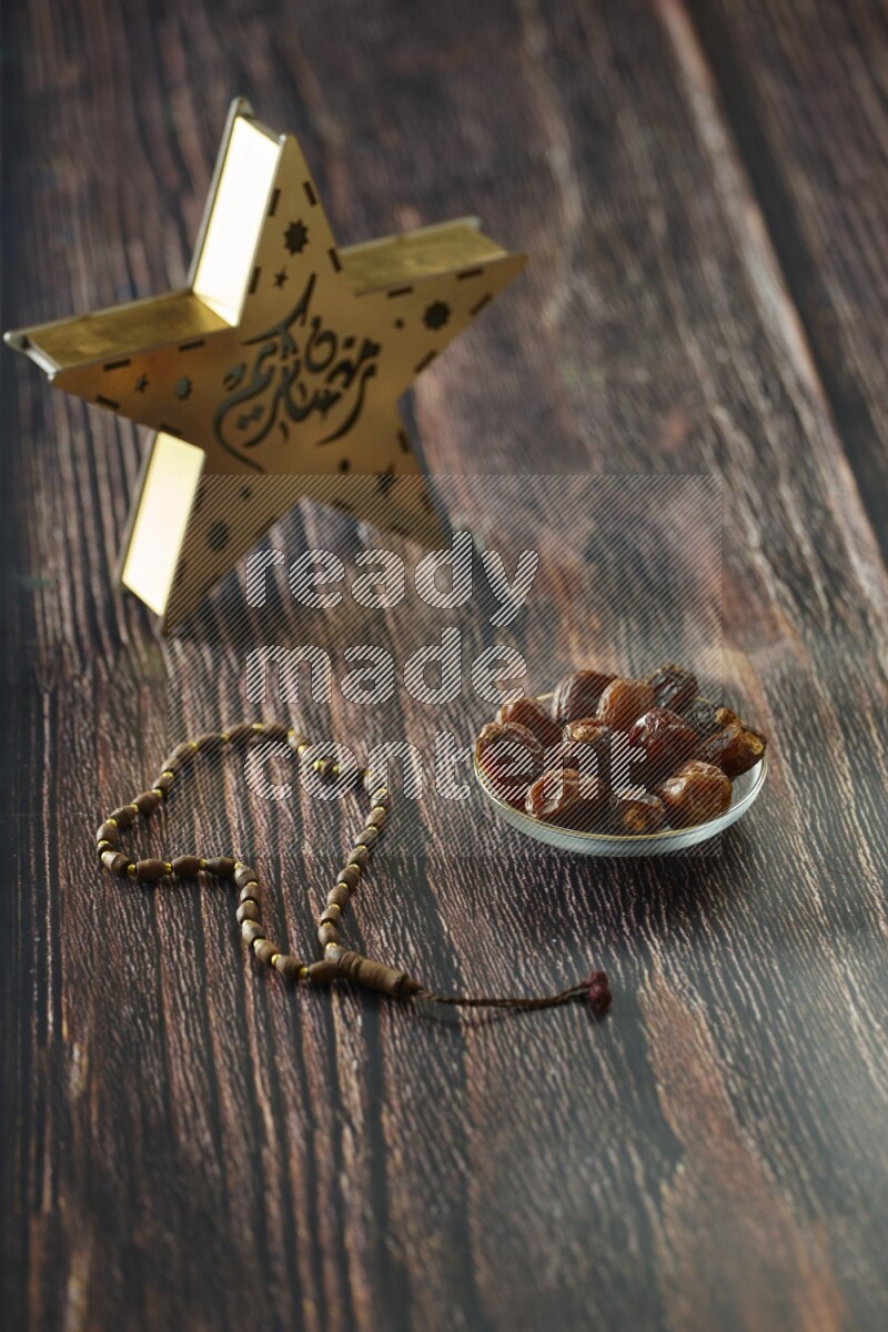 A wooden golden star lantern with different drinks, dates, nuts, prayer beads and quran on brown wooden background