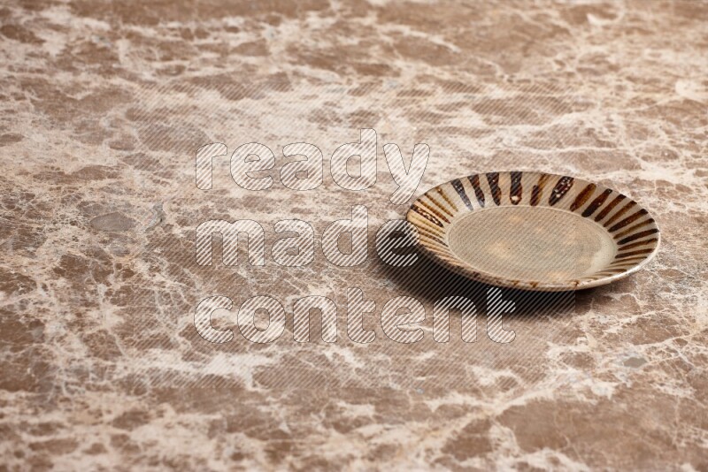 A multicolored pottery plate on beige marble background