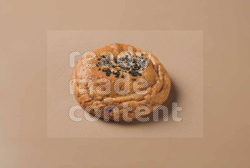 a whole Hasawi cookie with grains on a brown background