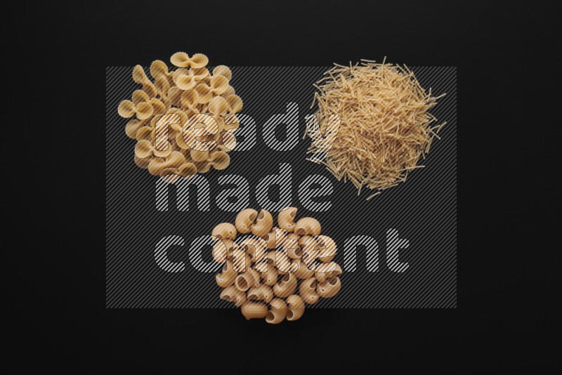 Different pasta types in bunches on black background