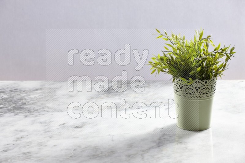 Artificial plant in green decorative pot on grey marble background