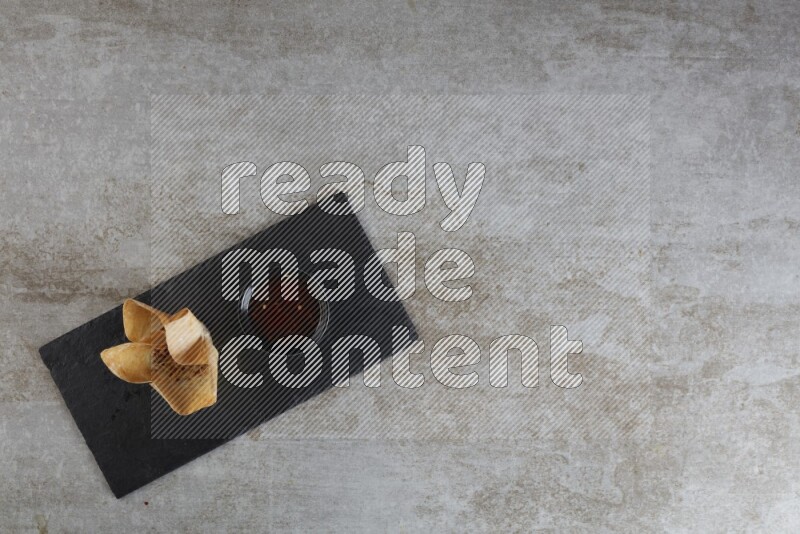 wonton cups with soy sauce ramkin on rectangle slate on grey textured counter top