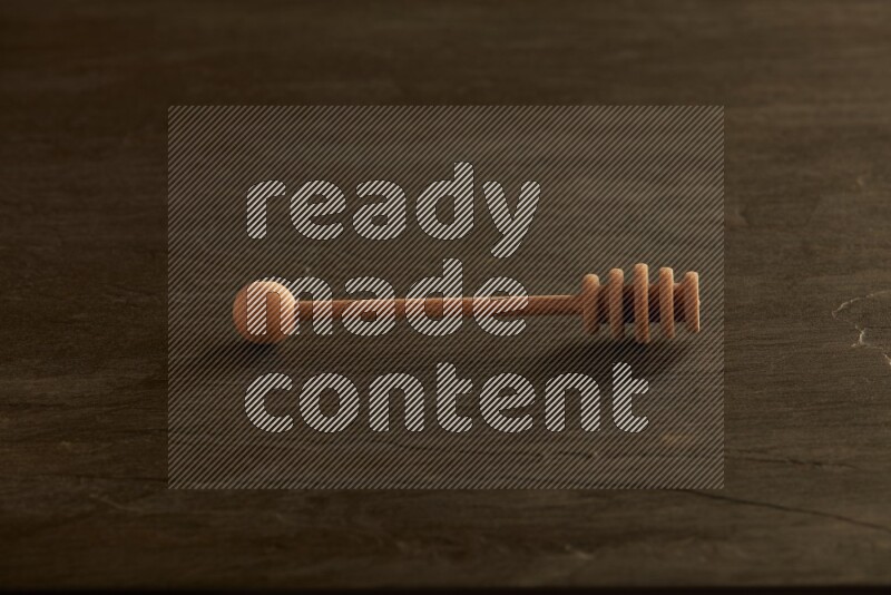 Wooden honey dipper on black slate background
