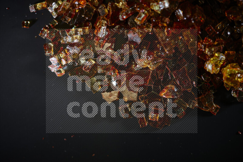 Transparent orange fragments of glass scattered on a black background