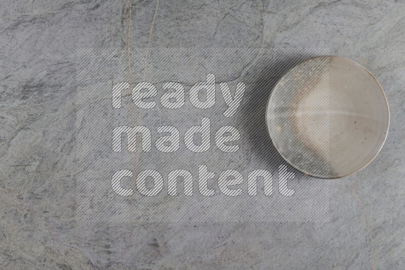 A multicolored pottery plate on grey marble background