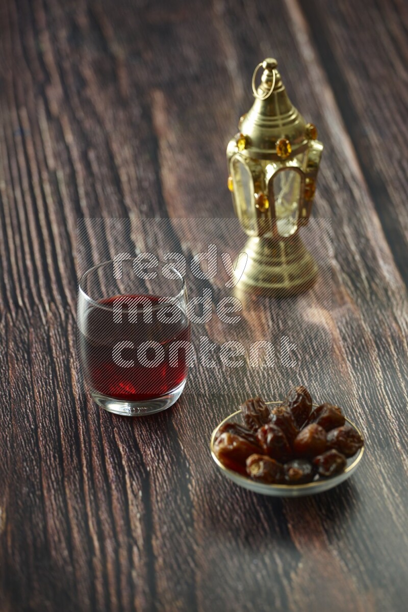 A golden lantern with different drinks, dates, nuts, prayer beads and quran on brown wooden background