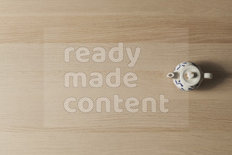 A pottery teapot on light wooden background