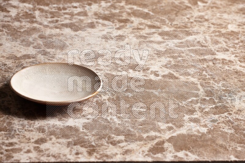 A beige pottery plate on beige marble background