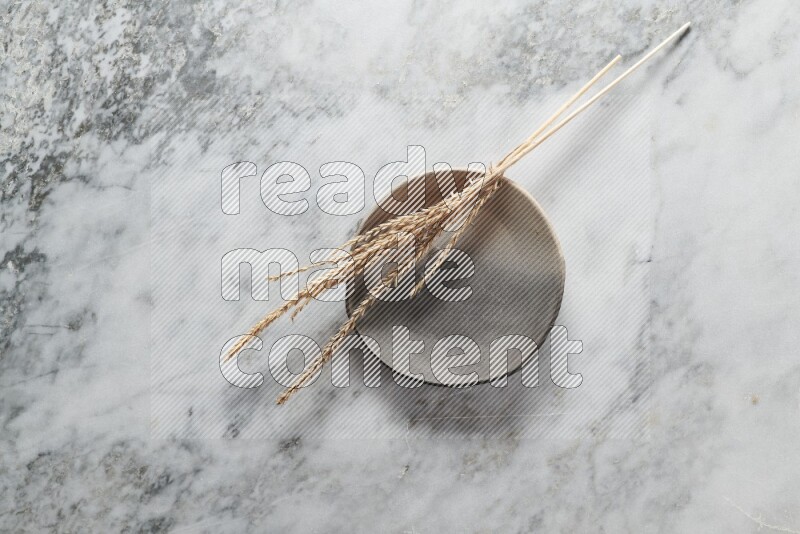 Wheat stalks on multicolored pottery plate on grey marble background
