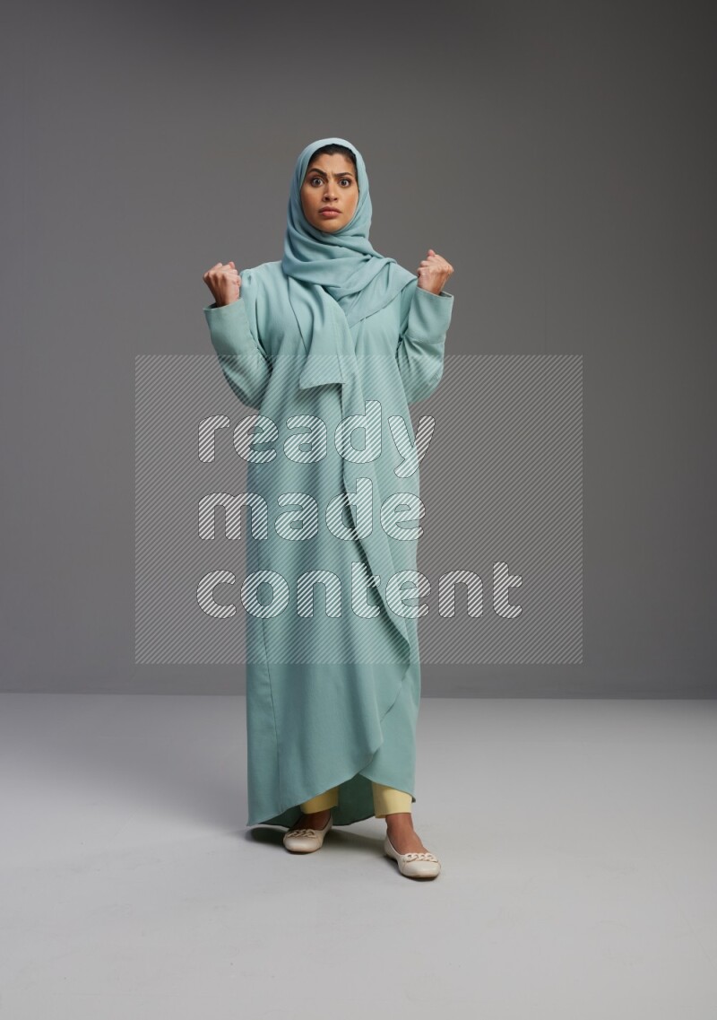 Saudi Woman wearing Abaya standing interacting with the camera on Gray background